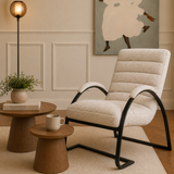 Beige armchair in a living room setting with a side table and lamp.