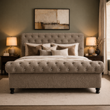 Gray upholstered bed in a bedroom with lamps and artwork on the wall.